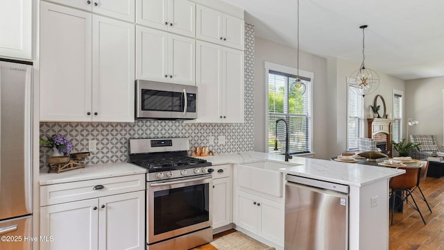 359 N Leak St, Southern Pines, NC 28387 - kitchen featuring appliances with stainless steel finishes, a sink, a peninsula, tasteful backsplash, and white cabinetry