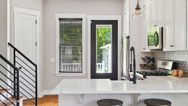 359 N Leak St, Southern Pines, NC 28387 - kitchen with appliances with stainless steel finishes, a breakfast bar area, a peninsula, decorative backsplash, and white cabinets