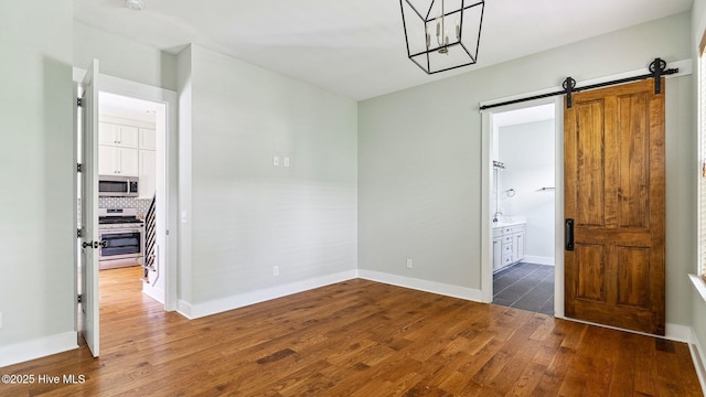 359 N Leak St, Southern Pines, NC 28387 - spare room with wood finished floors, baseboards, a barn door, and a chandelier