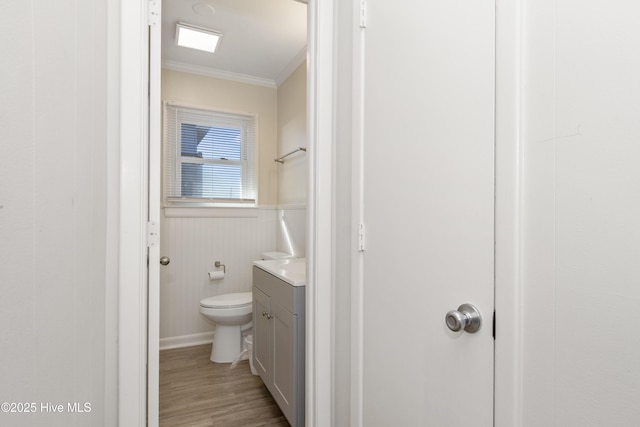 901 Ocean Dr, Emerald Isle, NC 28594 - bathroom featuring ornamental molding, vanity, toilet, wood finished floors, and a wainscoted wall