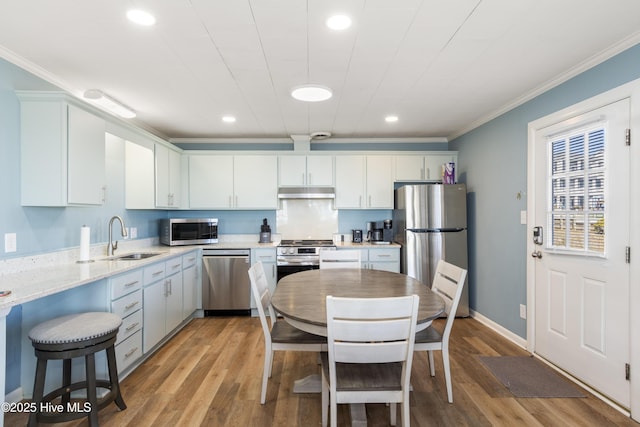 901 Ocean Dr, Emerald Isle, NC 28594 - kitchen featuring stainless steel appliances, a sink, under cabinet range hood, ornamental molding, and light wood finished floors