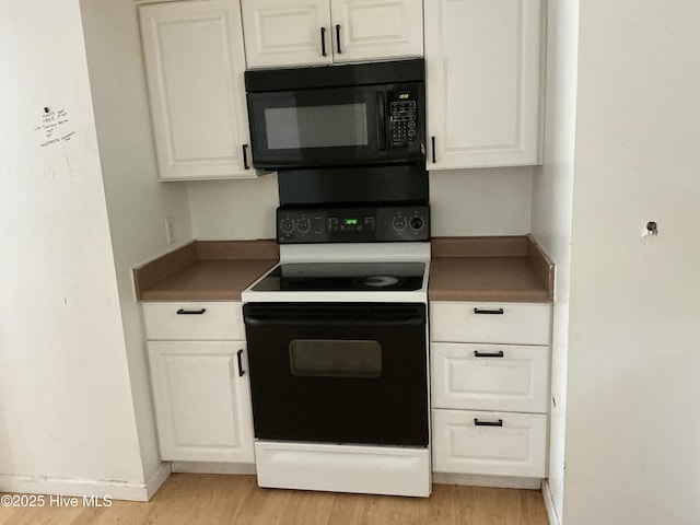 102 Tanglewood Dr, Jacksonville, NC 28540 - kitchen with electric range, black microwave, light wood-style floors, and white cabinetry