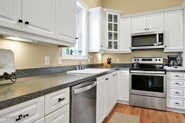 3853 Winding Vine Way, Southport, NC 28461 - kitchen featuring appliances with stainless steel finishes, white cabinetry, glass insert cabinets, and dark countertops