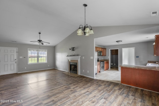 308 Big Tree Ln, Chinquapin, NC 28521 - unfurnished living room with wood finished floors, a fireplace, ceiling fan, high vaulted ceiling, and a chandelier