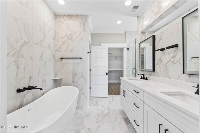 1711 Hemingway Dr SW, Ocean Isle Beach, NC 28469 - full bath featuring marble finish floors, a soaking tub, double vanity, a walk in closet, and tile walls