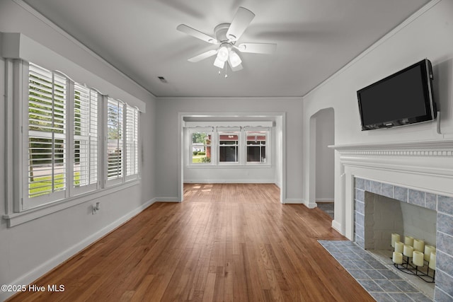 822 Chattawka Ln, New Bern, NC 28560 - unfurnished living room featuring wood finished floors, a ceiling fan, a fireplace, baseboards, and arched walkways
