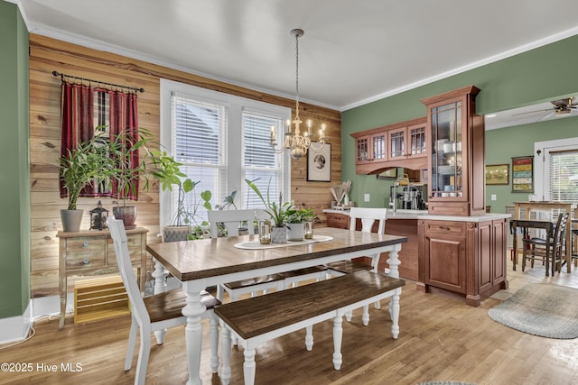 2008 Market St, Wilmington, NC 28403 - dining space with wood walls, a chandelier, ornamental molding, a ceiling fan, and light wood finished floors