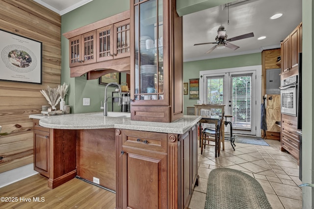 2008 Market St, Wilmington, NC 28403 - kitchen with stainless steel oven, crown molding, ceiling fan, glass insert cabinets, and brown cabinets