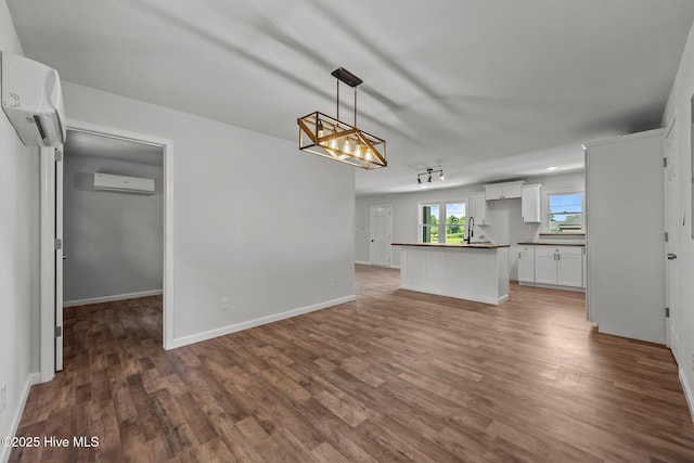 1496 Kellum Loop Rd, Jacksonville, NC 28546 - kitchen featuring dark countertops, dark wood finished floors, white cabinets, a wall unit AC, and open floor plan