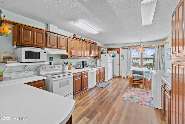 210 W Beach Dr, Oak Island, NC 28465 - kitchen with white appliances, under cabinet range hood, light wood-type flooring, light countertops, and a textured ceiling