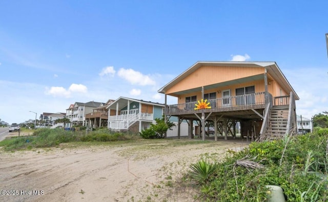 210 W Beach Dr, Oak Island, NC 28465 - back of house featuring a carport, stairs, dirt driveway, and a porch