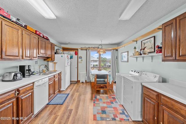 210 W Beach Dr, Oak Island, NC 28465 - kitchen featuring white appliances, independent washer and dryer, a textured ceiling, and brown cabinetry