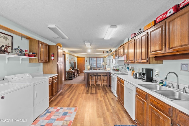 210 W Beach Dr, Oak Island, NC 28465 - kitchen with independent washer and dryer, white appliances, brown cabinets, light countertops, and a textured ceiling