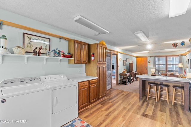 210 W Beach Dr, Oak Island, NC 28465 - laundry area featuring cabinet space, a textured ceiling, light wood-style flooring, and separate washer and dryer