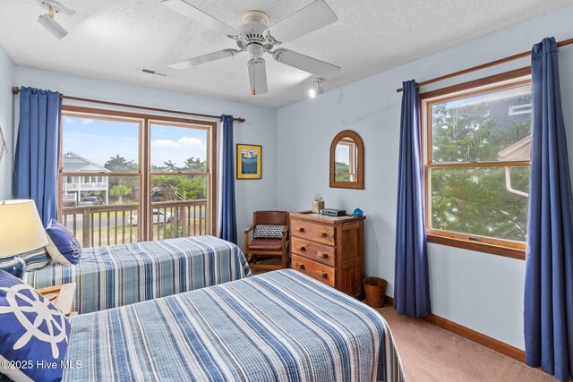 210 W Beach Dr, Oak Island, NC 28465 - carpeted bedroom featuring multiple windows, a textured ceiling, rail lighting, and ceiling fan