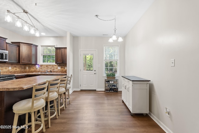 5709 Burgaw Hwy, Maple Hill, NC 28454 - kitchen featuring stainless steel appliances, dark wood finished floors, a breakfast bar area, tasteful backsplash, and dark brown cabinetry