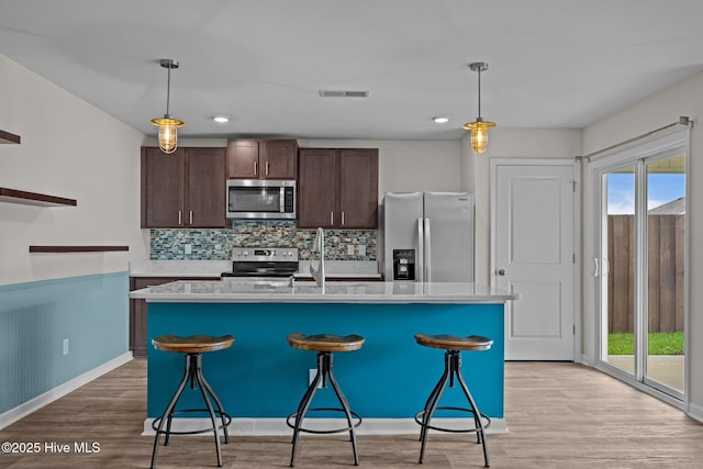 694 Chester Way NE, Leland, NC 28451 - kitchen featuring appliances with stainless steel finishes, dark brown cabinets, light countertops, a kitchen breakfast bar, and pendant lighting