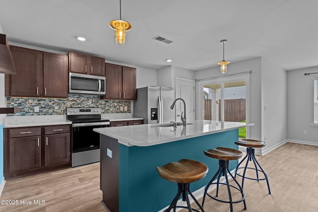 694 Chester Way NE, Leland, NC 28451 - kitchen with stainless steel appliances, light wood finished floors, decorative backsplash, decorative light fixtures, and a breakfast bar