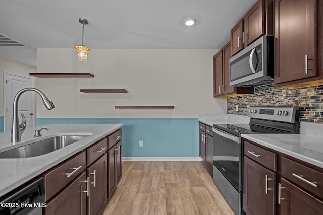 694 Chester Way NE, Leland, NC 28451 - kitchen featuring stainless steel appliances, light wood-type flooring, a wainscoted wall, hanging light fixtures, and light stone counters