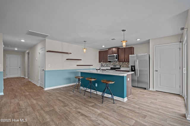 694 Chester Way NE, Leland, NC 28451 - kitchen featuring stainless steel appliances, light countertops, light wood-style floors, a breakfast bar area, and dark brown cabinetry