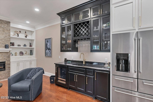 2270 Midland Rd, Pinehurst, NC 28374 - indoor wet bar featuring high end refrigerator, crown molding, wine cooler, wood finished floors, and a stone fireplace