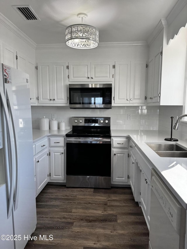 4704 S Va Dare Trl, Nags Head, NC 27959 - kitchen with appliances with stainless steel finishes, dark wood finished floors, light countertops, white cabinets, and ornamental molding