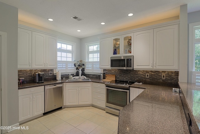 1209 Moultrie Dr NW, Calabash, NC 28467 - kitchen featuring stainless steel appliances, a sink, backsplash, white cabinets, and light tile patterned floors