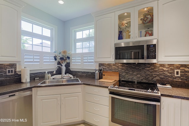 1209 Moultrie Dr NW, Calabash, NC 28467 - kitchen featuring stainless steel appliances, a sink, white cabinetry, decorative backsplash, and glass insert cabinets