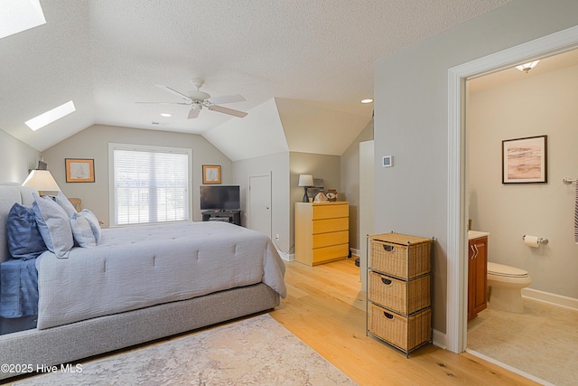 1209 Moultrie Dr NW, Calabash, NC 28467 - bedroom with a skylight, light wood-type flooring, lofted ceiling, connected bathroom, and a textured ceiling