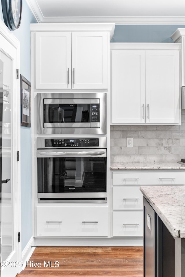 8116 Barstow Ln, Wilmington, NC 28411 - kitchen featuring stainless steel appliances, white cabinets, ornamental molding, backsplash, and light stone countertops