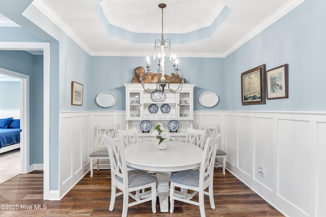 8116 Barstow Ln, Wilmington, NC 28411 - dining space featuring a chandelier, a decorative wall, a tray ceiling, dark wood-type flooring, and crown molding