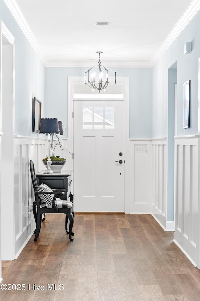 8116 Barstow Ln, Wilmington, NC 28411 - entrance foyer featuring a decorative wall, a chandelier, crown molding, wainscoting, and wood finished floors
