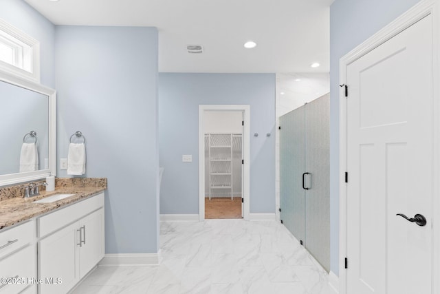 8116 Barstow Ln, Wilmington, NC 28411 - bathroom featuring a stall shower, vanity, a spacious closet, marble look tile flooring, and recessed lighting