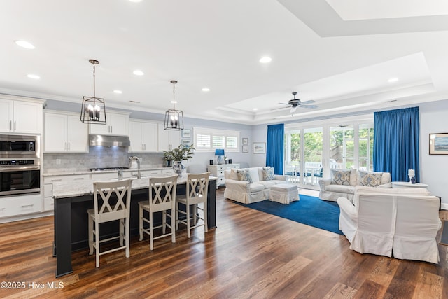 8116 Barstow Ln, Wilmington, NC 28411 - living area featuring a raised ceiling, recessed lighting, ornamental molding, ceiling fan, and dark wood-style floors