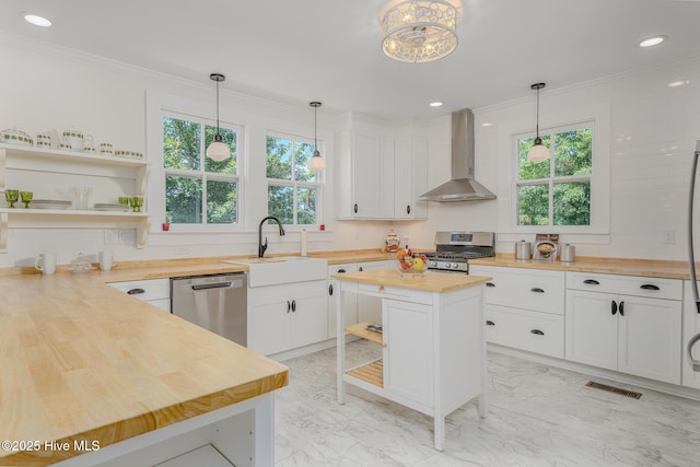 405 Hancock St, New Bern, NC 28560 - kitchen featuring butcher block countertops, wall chimney exhaust hood, appliances with stainless steel finishes, open shelves, and a sink