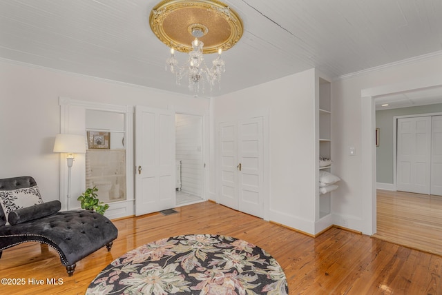 405 Hancock St, New Bern, NC 28560 - sitting room with a chandelier, wood finished floors, crown molding, baseboards, and built in shelves