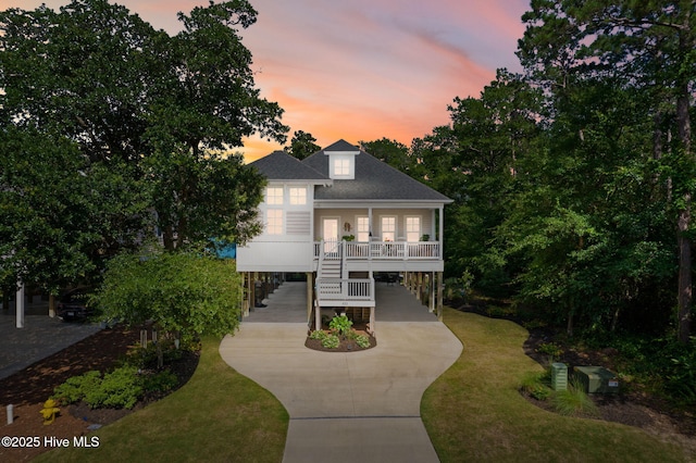 322 NE 42nd St, Oak Island, NC 28465 - coastal inspired home featuring a carport, stairway, covered porch, concrete driveway, and a shingled roof