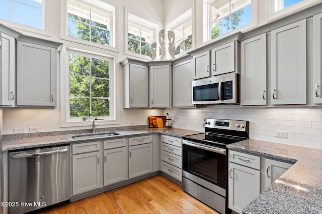 322 NE 42nd St, Oak Island, NC 28465 - kitchen featuring appliances with stainless steel finishes, gray cabinetry, tasteful backsplash, and light wood-type flooring