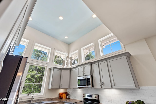 322 NE 42nd St, Oak Island, NC 28465 - kitchen with appliances with stainless steel finishes, gray cabinets, plenty of natural light, backsplash, and a high ceiling