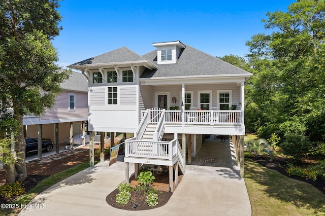 322 NE 42nd St, Oak Island, NC 28465 - coastal home featuring a carport, driveway, a shingled roof, covered porch, and stairs