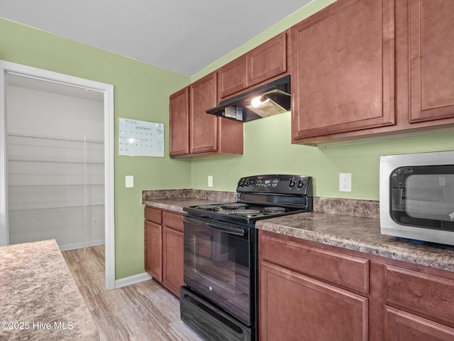 301 Stella Bridgeway Dr, Stella, NC 28582 - kitchen with electric range, under cabinet range hood, stainless steel microwave, light wood-style flooring, and brown cabinets