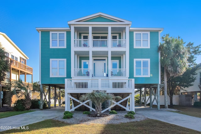 2911 E Pelican Dr, Oak Island, NC 28465 - raised beach house with a carport, a balcony, concrete driveway, and a porch