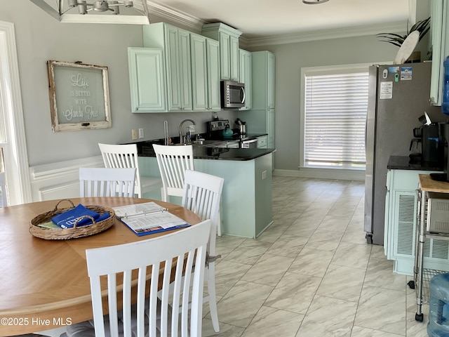 2911 E Pelican Dr, Oak Island, NC 28465 - kitchen featuring stainless steel appliances, light marble finish floors, dark countertops, crown molding, and a peninsula
