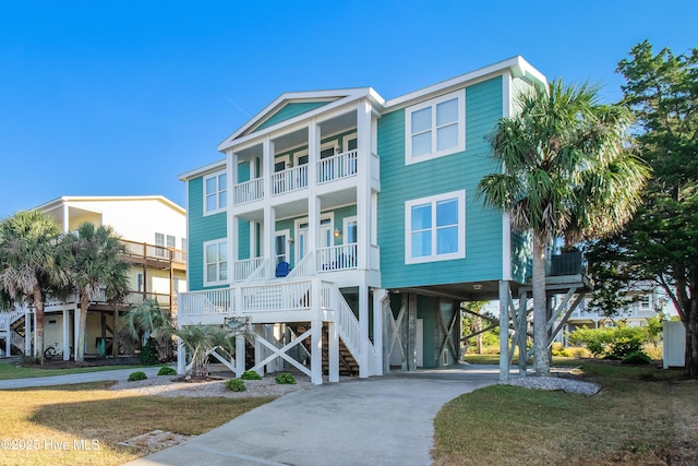 2911 E Pelican Dr, Oak Island, NC 28465 - raised beach house featuring a balcony, a carport, driveway, and a porch