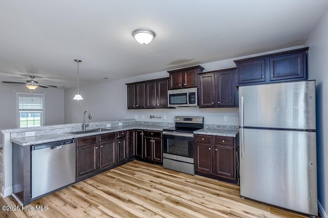 108 Meadow Way, Havelock, NC 28532 - kitchen featuring stainless steel appliances, a peninsula, dark brown cabinets, light wood-type flooring, and light stone counters