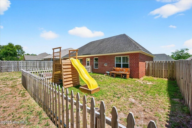 1009 Stonesthrow Ct, Leland, NC 28451 - rear view of property featuring a playground, a fenced backyard, brick siding, and roof with shingles