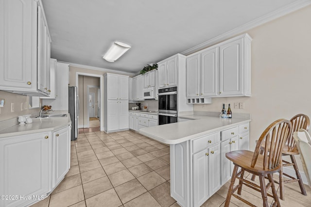 1910 Big Mill Rd, Williamston, NC 27892 - kitchen with stainless steel appliances, a peninsula, white cabinetry, light countertops, and ornamental molding