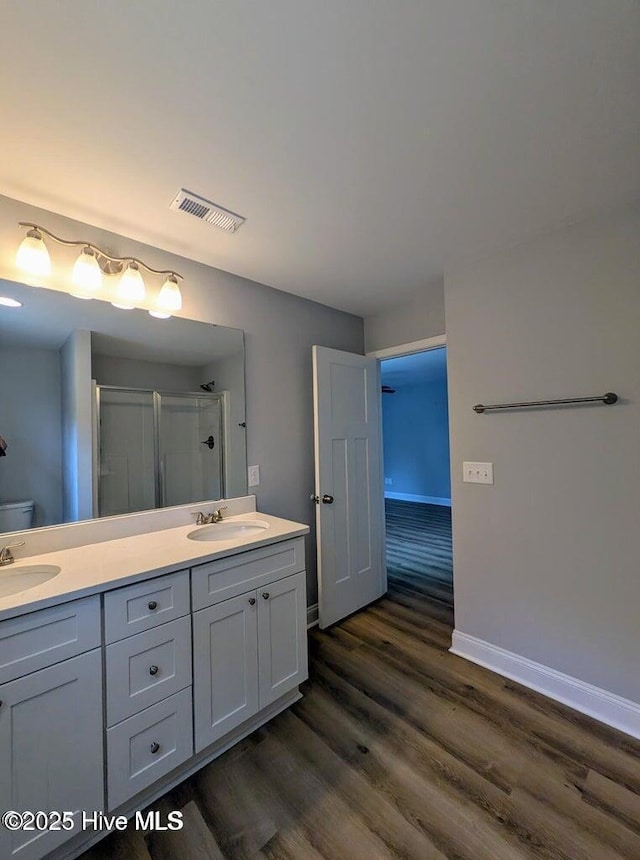 353 N Stephens St, Southern Pines, NC 28387 - bathroom with double vanity, wood finished floors, a shower with shower door, baseboards, and toilet