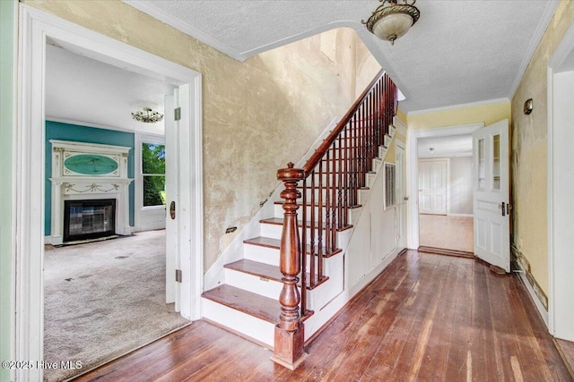 105 W Wayne St, Fremont, NC 27830 - stairway featuring hardwood / wood-style flooring, a textured ceiling, ornamental molding, and a glass covered fireplace