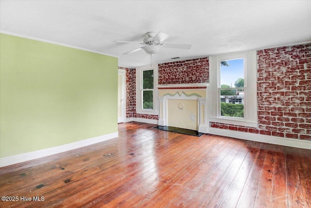 105 W Wayne St, Fremont, NC 27830 - unfurnished living room featuring ceiling fan, wood-type flooring, a textured ceiling, and brick wall